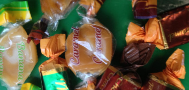 Torino, via Bava. Un sacchetto di caramelle  sull'orlo di un cassonetto stradale della plastica.